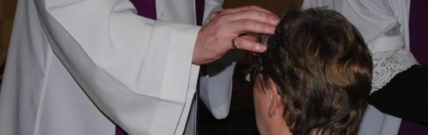 Priest anointing the head of a man with oil